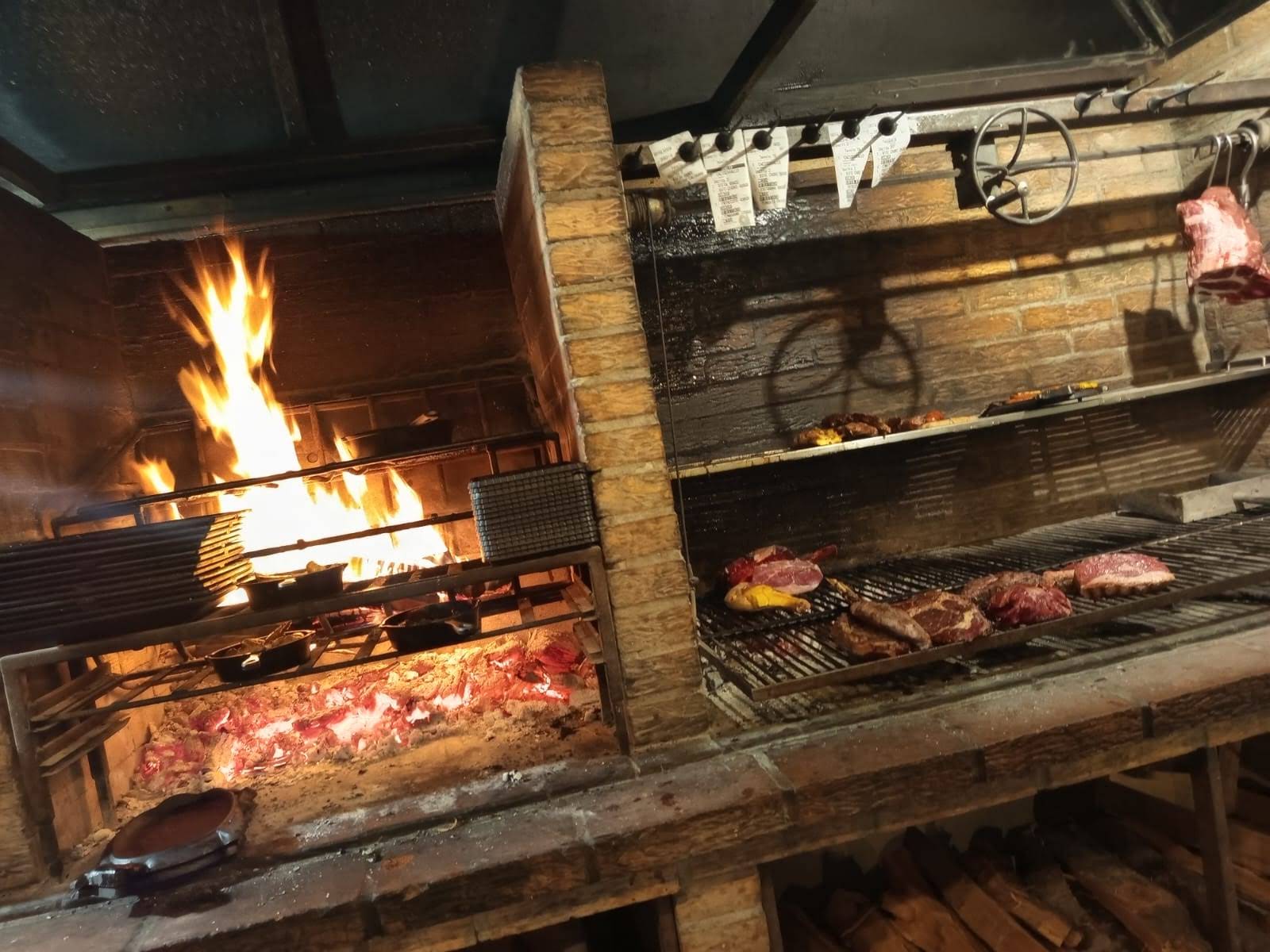 Fuego vivo del asado — llamas y brasa sobre la parrilla argentina de La Stalla