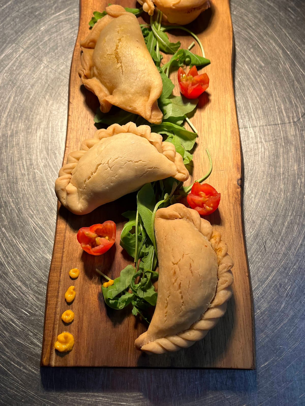 Empanadas artesanales de La Stalla — rellenas de carne, verduras y pollo sobre tabla de madera
